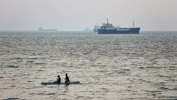 BANDAR ABBAS, IRAN - APRIL 22: Two boys paddle-board in the sea as ships are anchored near the shoreline on April 22, 2026 in Bandar Abbas, Iran. Bandar Abbas is a port city and the capital of Hormozgan Province, along the Persian Gulf and Strait of Hormu