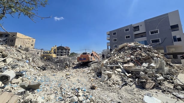 Diggers are seen digging through debris 
