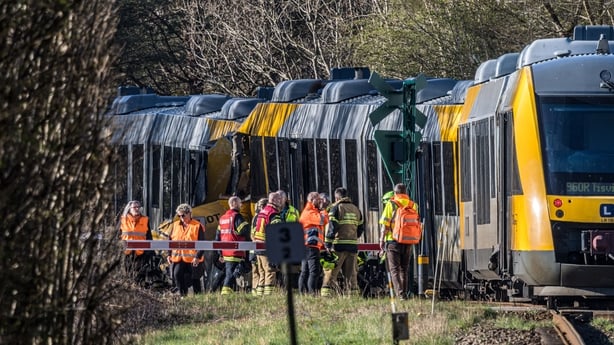 Rescue workers stand near two trains that collided