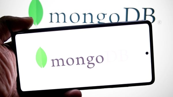 a MongoDB logo is seen displayed on a smartphone and in the background.