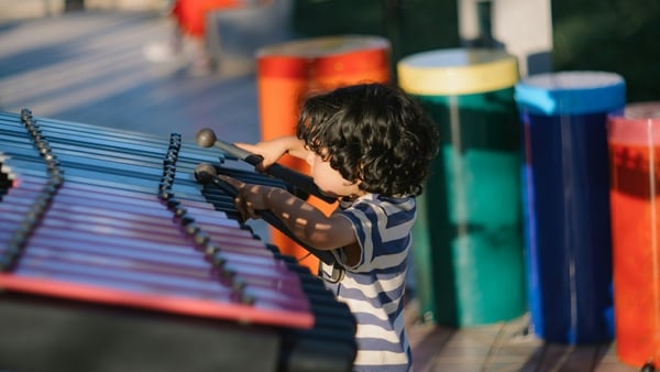 Child playing a xylophone in a public area (Photo by David Vilches on Unsplash)