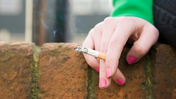 close up of a woman's hand holding a lit cigarette