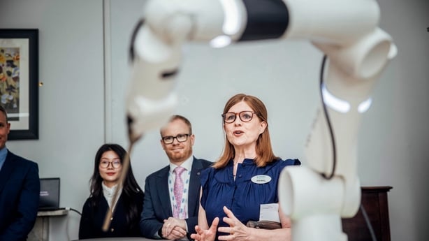 Robtic arm in hopsital wih people talking