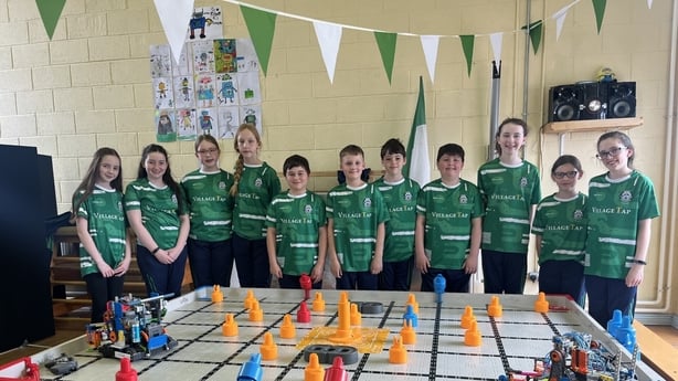 Children stand next to their project at school 