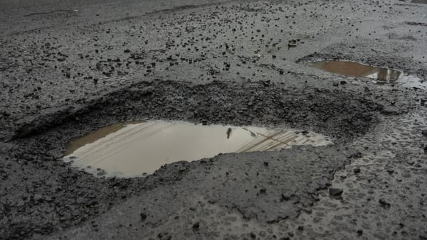 Pothole filled with rainwater on wet black asphalt road