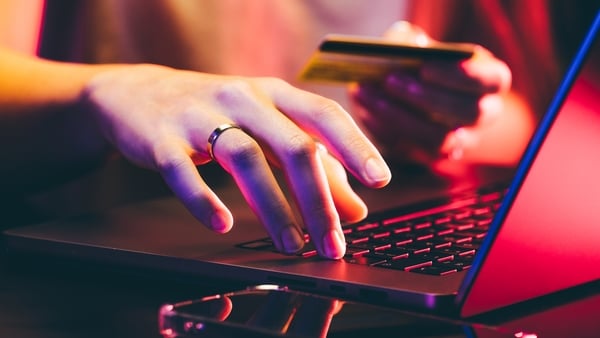 Hands holding a credit card and using a laptop under neon light. Online shopping.