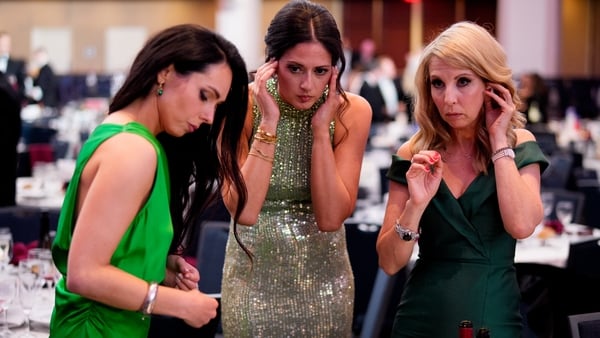 Courtney Subramanian (C) and Caitríona Perry (R) work from the ballroom following a shooting incident at the annual White House Correspondents Association Dinner