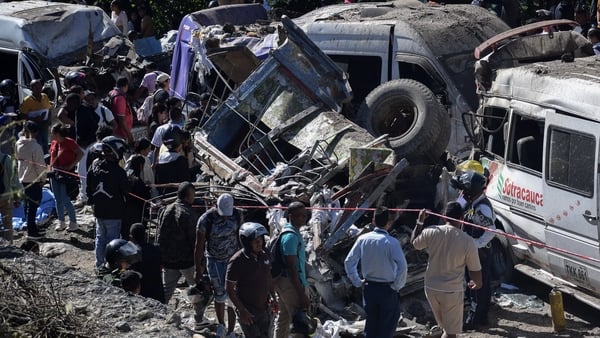 People stand next to vehicles destroyed by a bomb attack at El Tunel, on the Popayan-Cali road, in Cajibio, Cauca department, Colombia