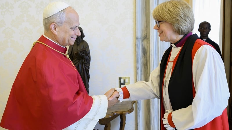 Image shows Pope Leo wearing red and white robes shaking hands with Archbishop Sarah Mullally, who is wearing white, black and red robes.