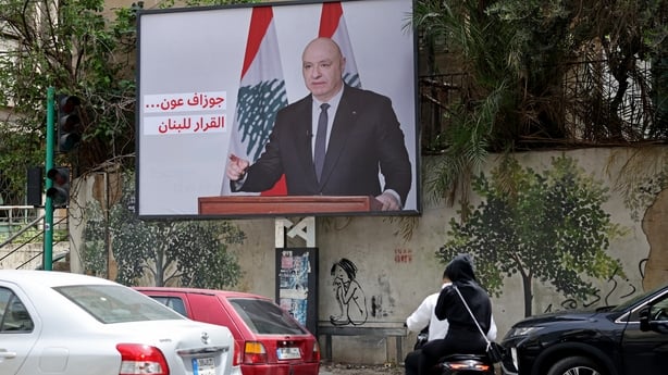 Vehicles drive past a billboard depicting Lebanon's President Joseph Aoun and reading "the choice is for Lebanon"