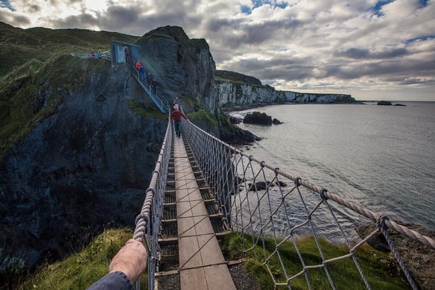 Visitors enjoying the walk across Carrick-a-Rede rope bridge with magnificent views of Fair Head.