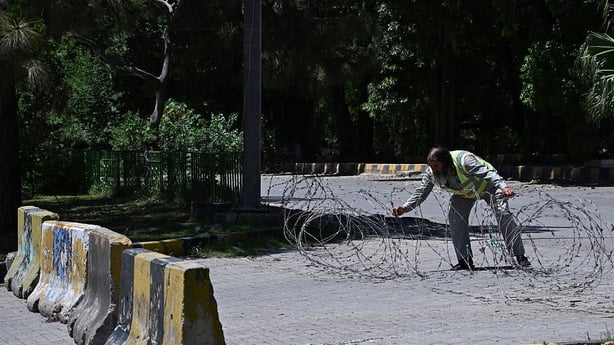 A traffic police personnel removes barricades from a closed street at the Red Zone area in Islamabad
