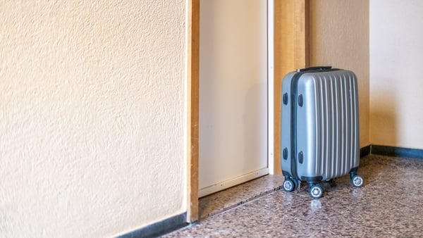 Suitcase beside a door, on a terrazzo floor in a hallway