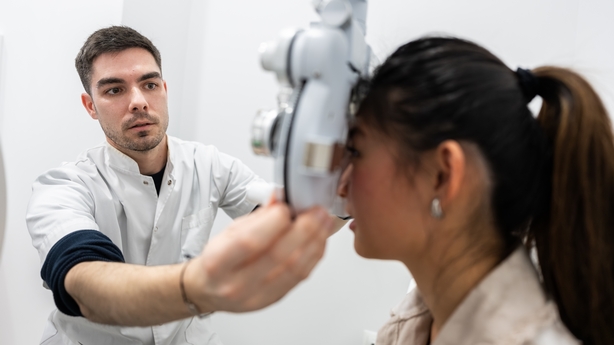 Optometrist using phoropter to examine patient's vision in an optical store