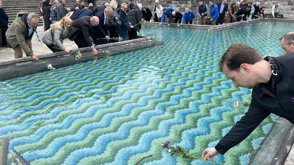 People place flowers in a fountain for Workers Memorial Day