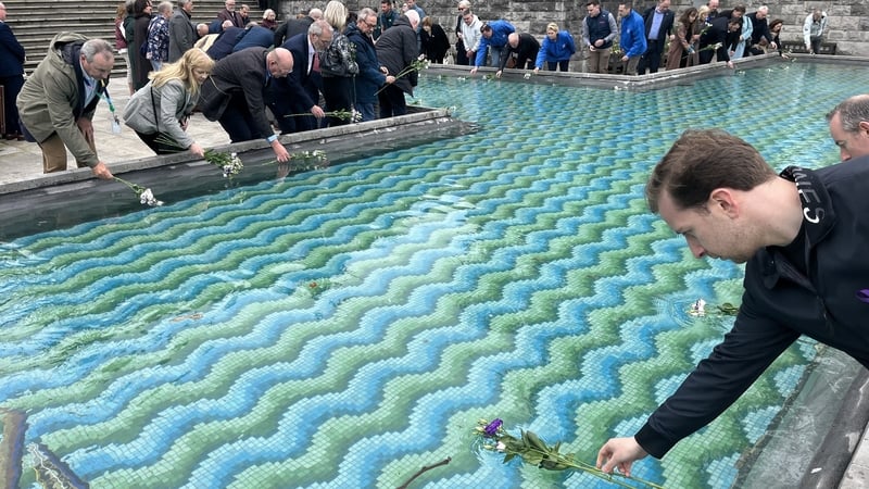 People place flowers in a fountain for Workers Memorial Day