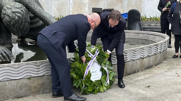 Two men lay a wreath to honor workers who died