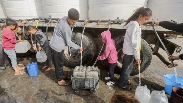 Palestinian children fill water containers from a mobile cistern in Gaza City 