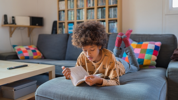 African- American boy reading a book on the sofa. Frontal view