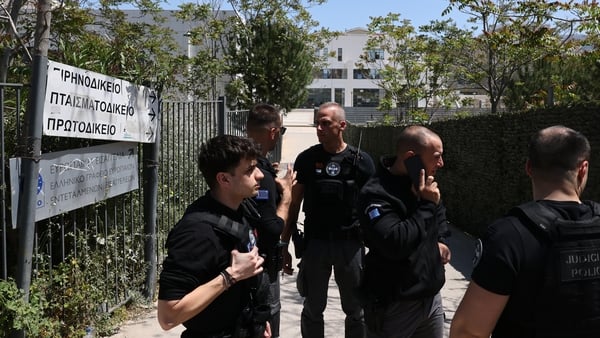 Police officers stand guard at the entrance of a courthouse after a gunman opened fire and wounded four people in Athens, Greece
