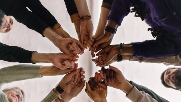 Low angle view of group of people in circle and holding their fists together during a group therapy session. People with fist put together during support group session.
