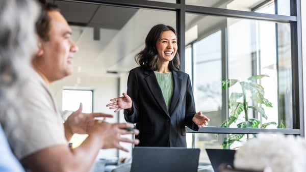 Young businesswoman speaking to colleagues in modern conference room