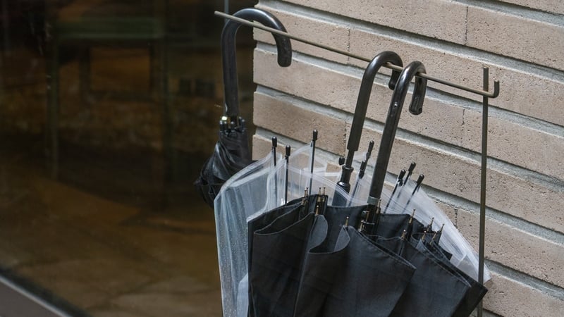 A number of umbrellas hanging on a stand on a rainy day