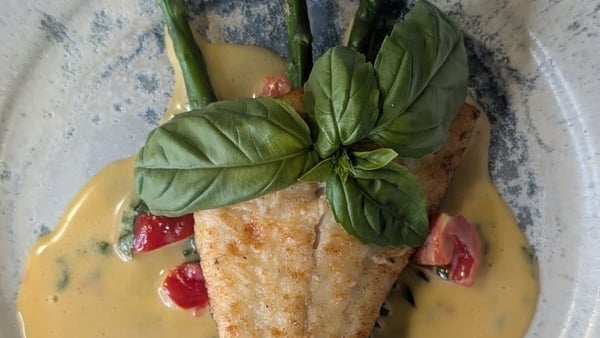 A fish dish with sauce and asparagus