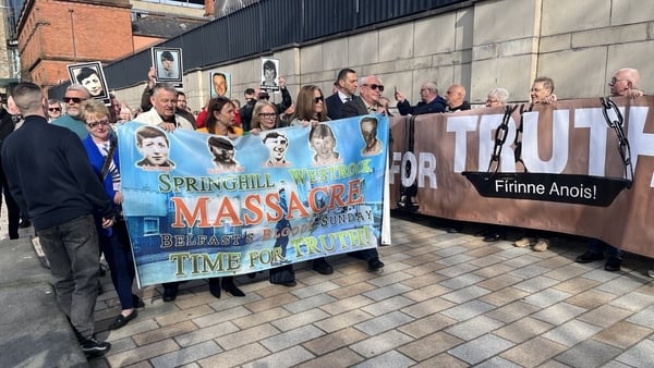 Family members hold up a placard with the victims' faces and names