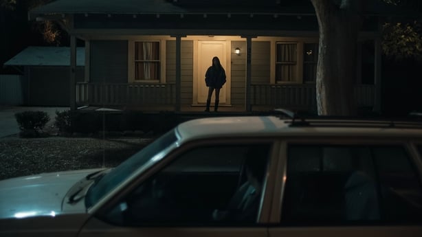 Inde Navarrette as Nikki waits on her doorstep while Michael Johnston as Bear stays in his car in Obsession. Photo: Focus Features/© 2026 FOCUS FEATURES LLC