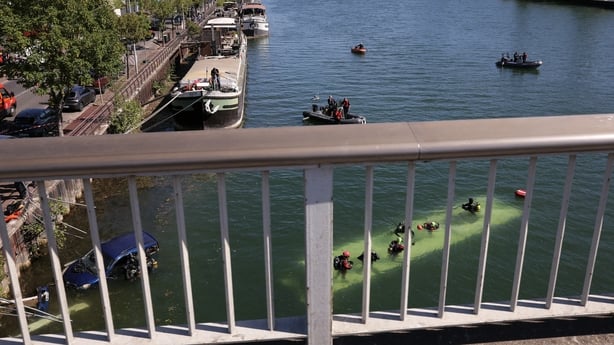 A view from a bridge of a bus submerged in a river