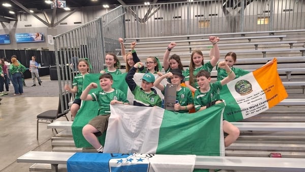 A pciture of the RNS Robotics team with their award alongside Ireland flags.