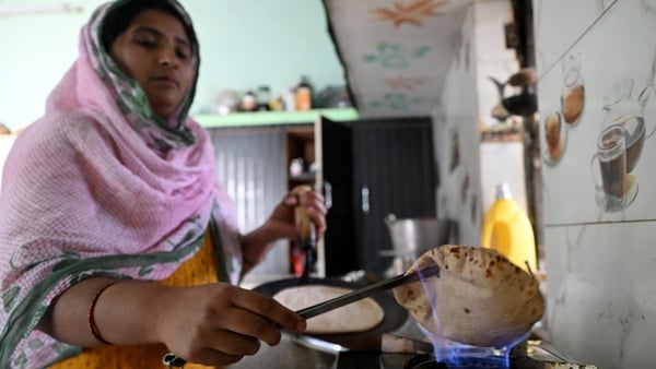 a woman cooks a chapati over an open flame