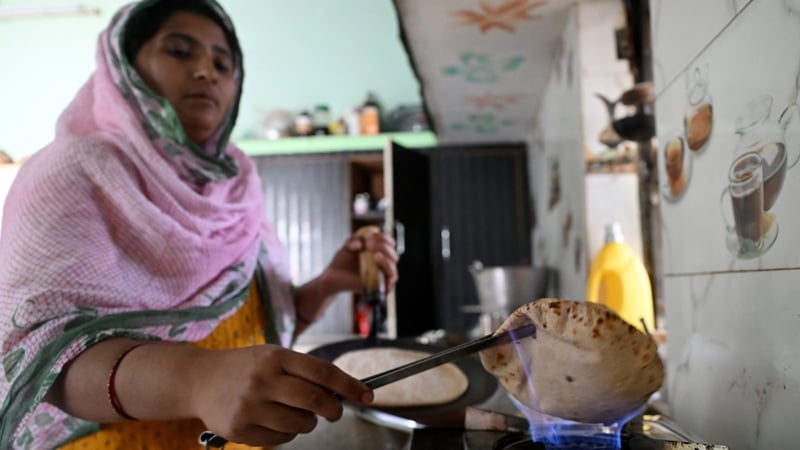 a woman cooks a chapati over an open flame