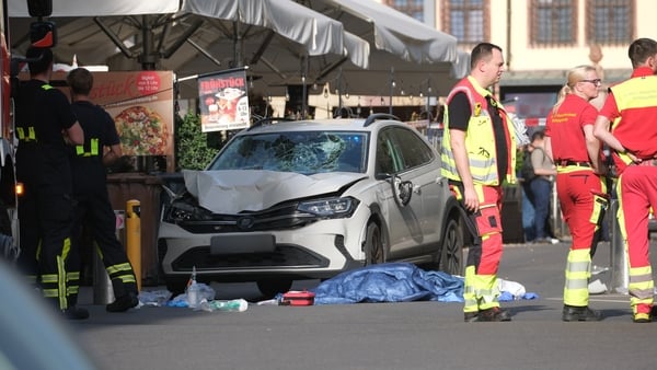 Rescue workers stand next to a damaged car in Leipzig.