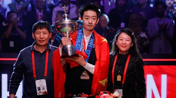 Wu Yize poses with the World Championship trophy alongside his parents at the Crucible