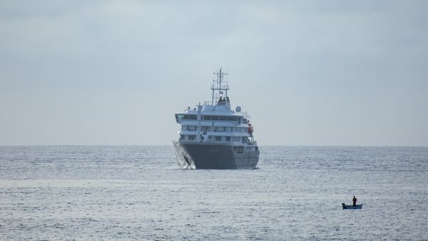 A fisherman sails past the cruise ship MV Hondius stationary off the port of Praia, the capital of Cape Verde