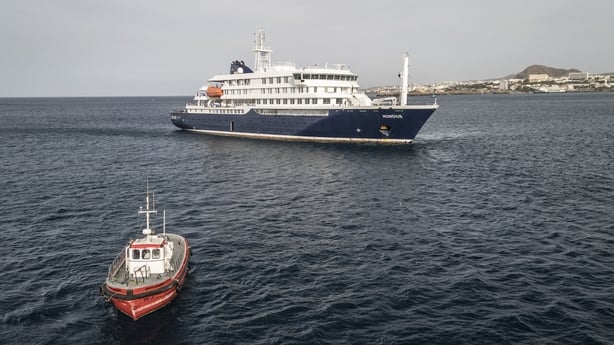 This aerial view shows a boat heading towards the port from the cruise ship MV Hondius, stationary off the port of Praia, the capital of Cape Verde