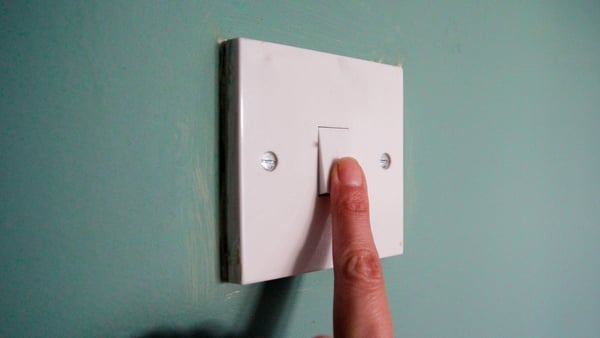 A close up of a finger tunring on a switch on a green wall