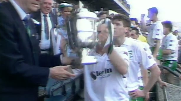 A large trophy being presented to a football tea,
