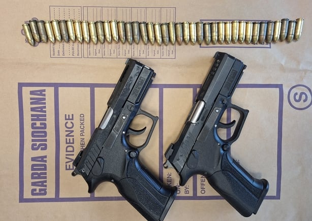Two semi automatic pistols and a line of bullets displayed on a garda evidence bag