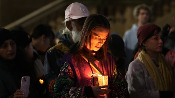 People hold candles as they stand in silence during a vigil in honour 