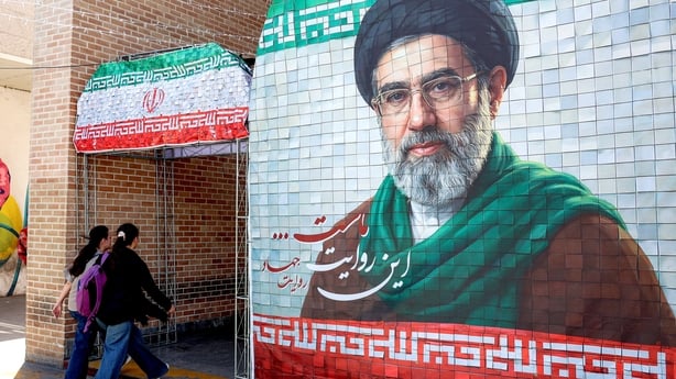 Women walk past a banner depicting Iran's current supreme leader Ayatollah Mojtaba Khamenei along a street Tehran on May 6, 2026.