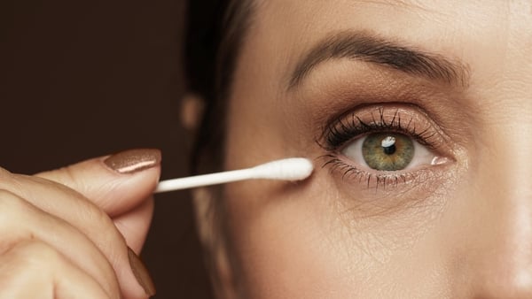 close up of woman correcting eye makeup with a cotton bud