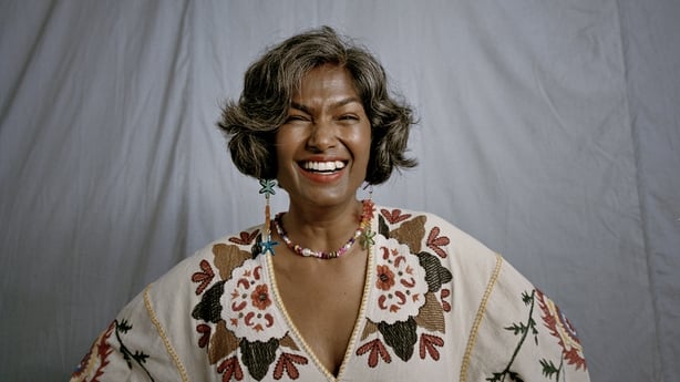 Portrait of happy mature woman wearing jewelry against gray background