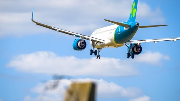 An Aer Lingus jet makes its final approach at a London airport under blue sky conditions