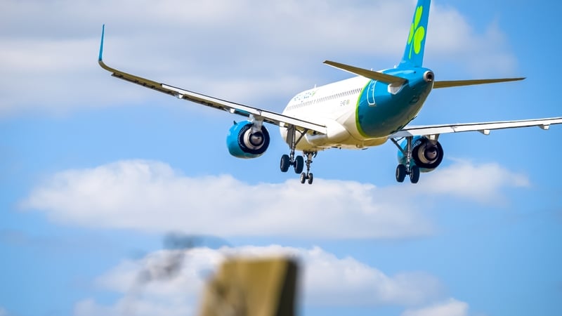 An Aer Lingus jet makes its final approach at a London airport under blue sky conditions