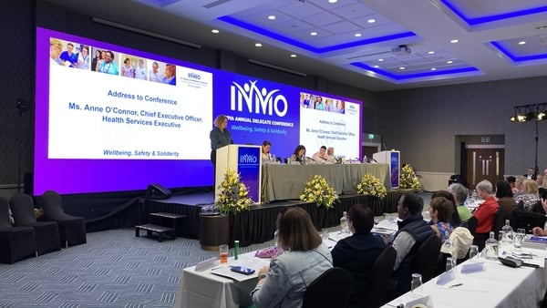 People listen as a person speaks at a conference with a power point presentation on a screen