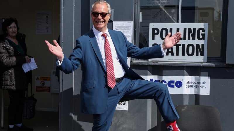 Reform UK leader Nigel Farage poses to show off his socks as he visits a polling station in Walton-on-the-Naze
