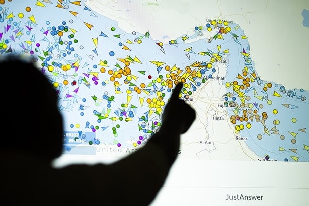 TOPSHOT - A photo illustration taken in Nicosia on May 4, 2026, shows a person in front of a large screen displaying vessel movements in the Strait of Hormuz on a ship-tracking website. Iran's navy fired 'warning shots' at US warships in the Strait of Hormuz on May 4, state media said, after the Ame